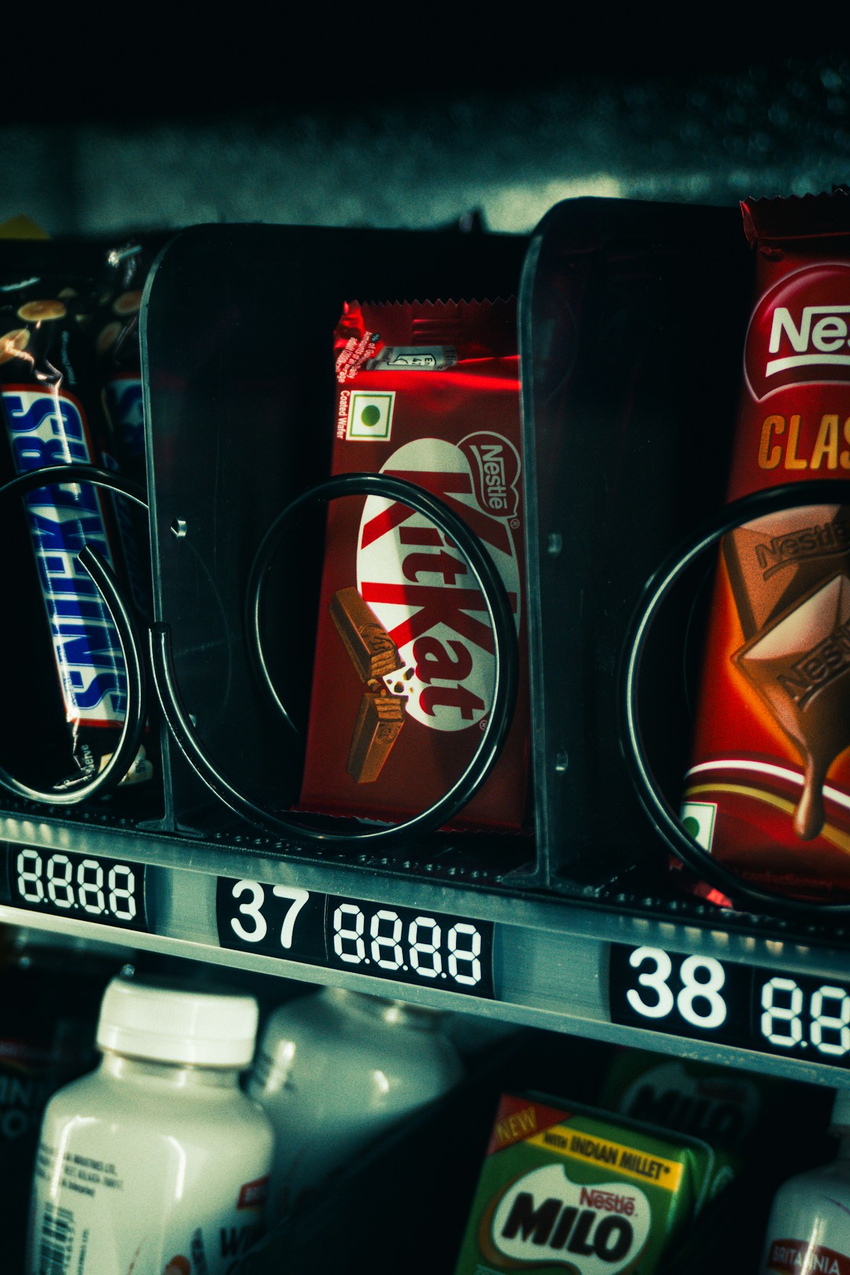 Close-up of candy bars behind the glass of a vending machine with digital price displays