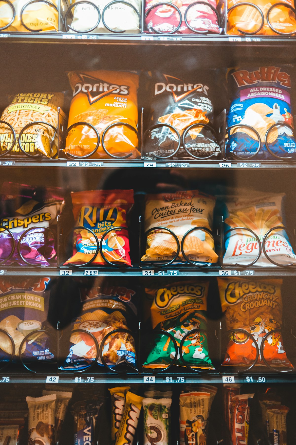 Shelves inside a snack vending machine filled with chips, crackers and candy bars